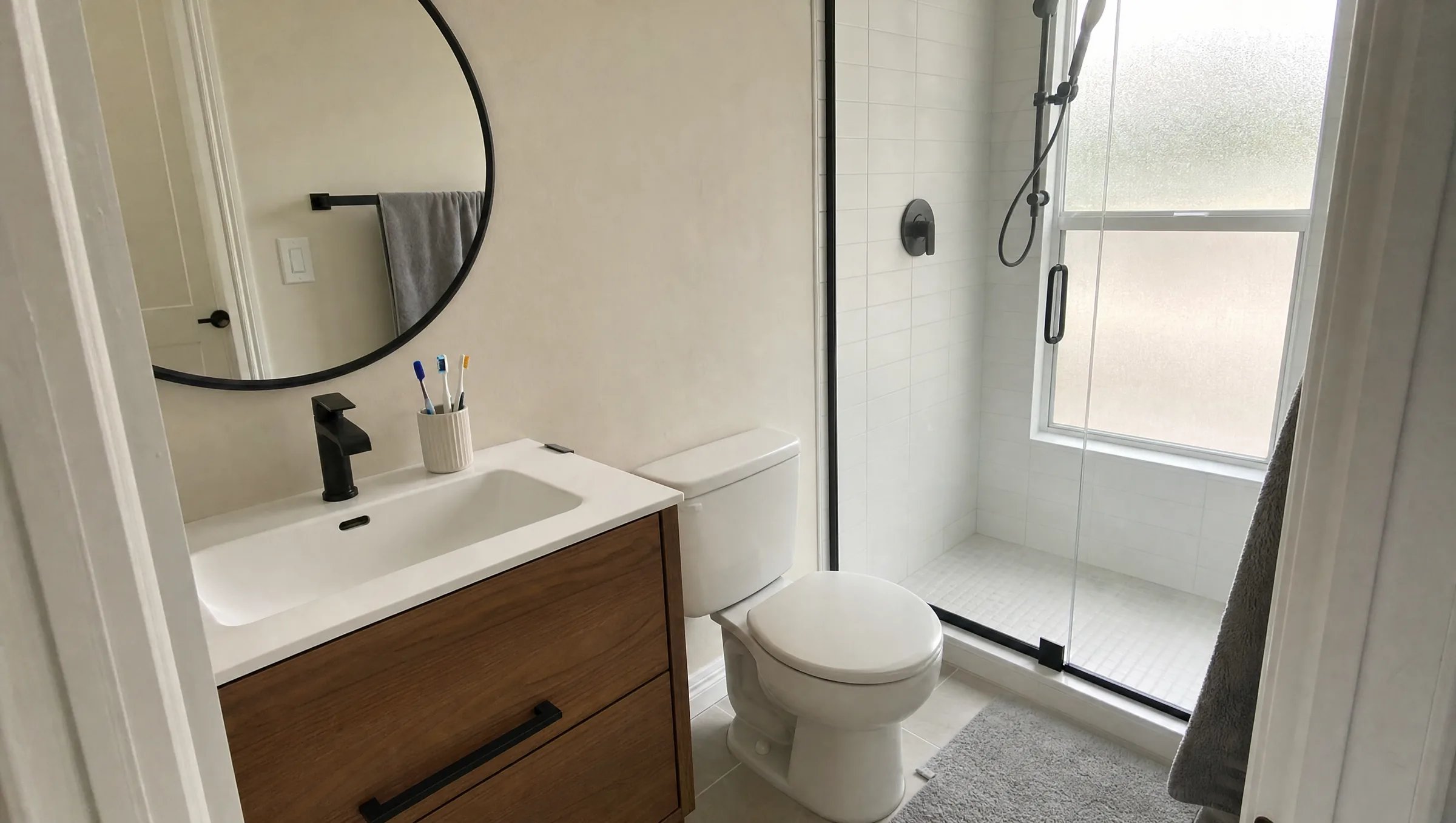 Compact primary bathroom with a single vanity, a glass shower and a frosted window