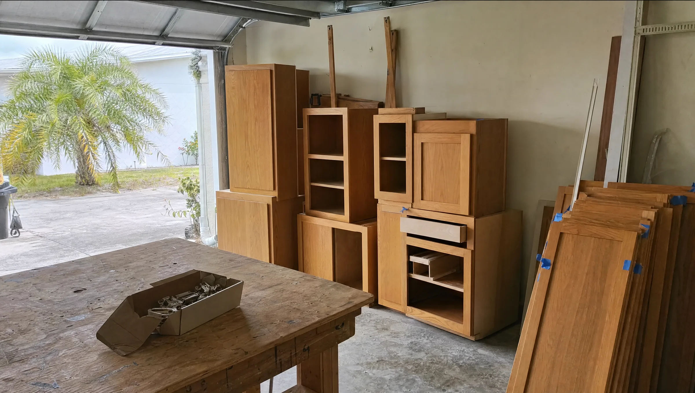 Salvaged kitchen cabinets with their doors stacked in a garage waiting to be reinstalled