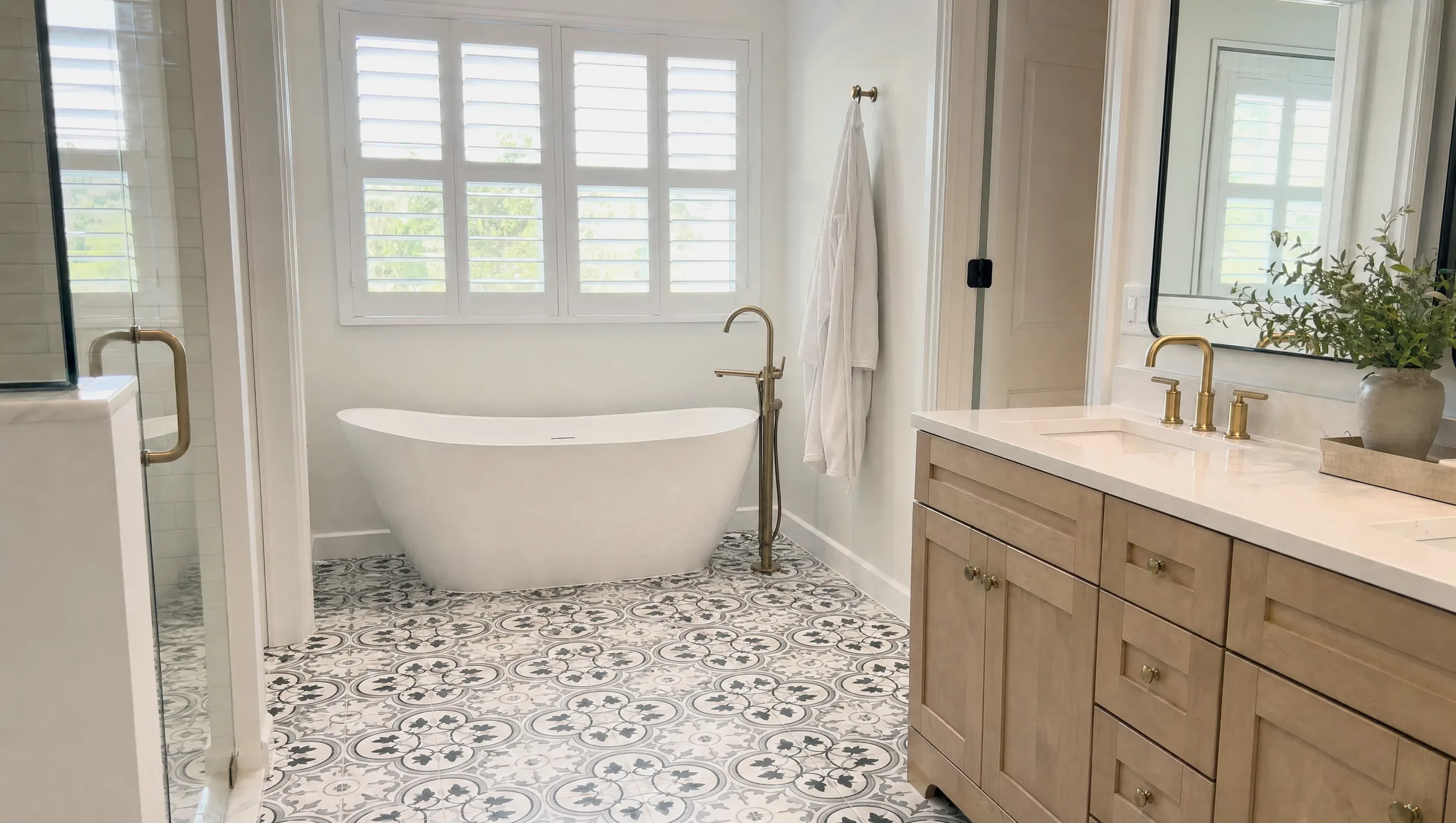 Bright primary bathroom with a freestanding tub under a window and patterned floor tile