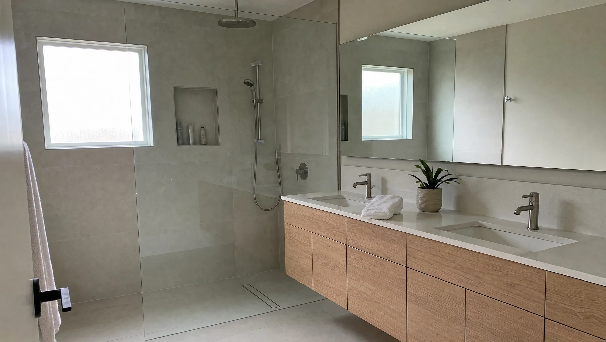 Spa-like primary bathroom with a frameless glass walk-in shower, large-format porcelain tile and a double floating vanity