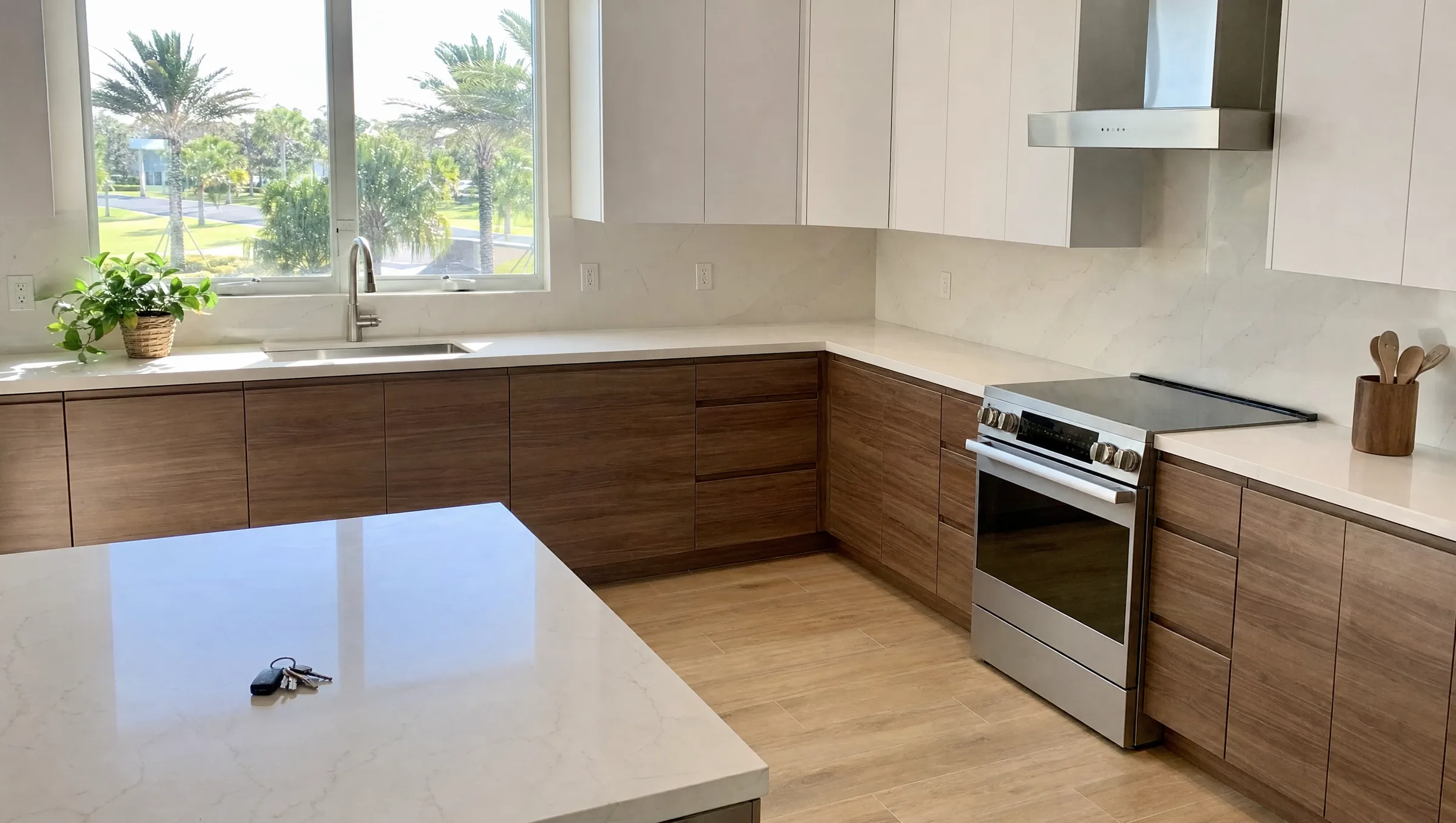 Modern kitchen with flat-panel walnut cabinets, white quartz counters and a window over the sink looking out to palm trees