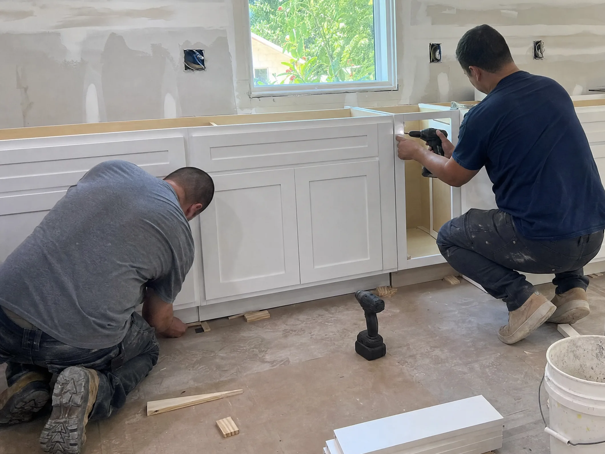 Installers leveling new base cabinets during a kitchen remodel before the countertops go on