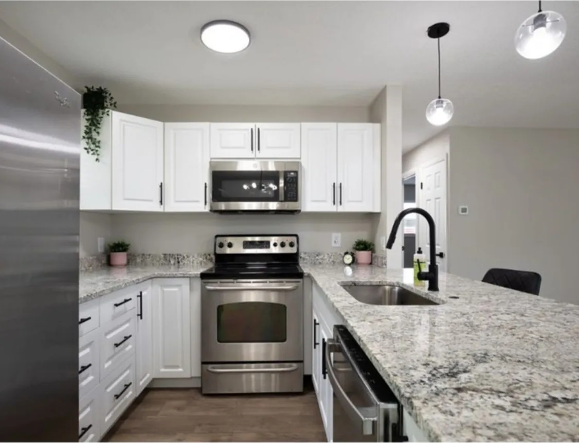 After: Kitchen after the remodel: oak cabinets replaced with white shaker cabinets and granite counters