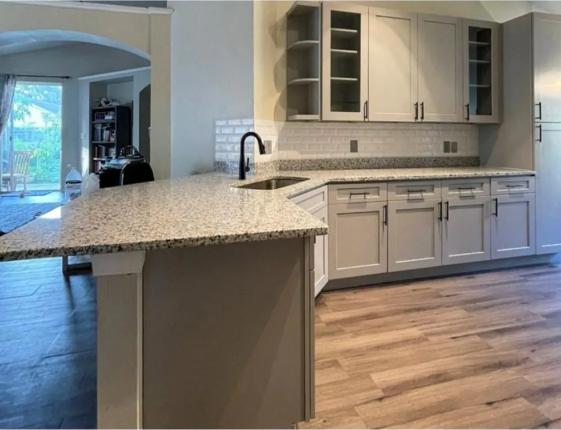 After: Kitchen after the remodel: red cherry cabinets replaced with gray shaker cabinets and granite