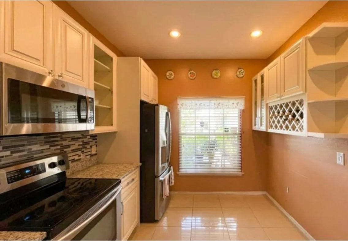 After: Kitchen after the remodel: oak galley kitchen replaced with cream cabinets and a mosaic backsplash