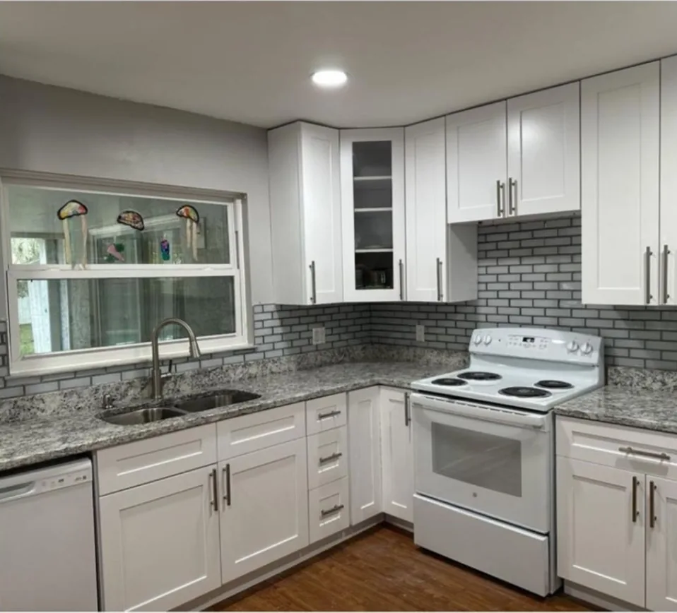After: Kitchen after the remodel: cluttered dated kitchen replaced with white shaker cabinets and a gray mosaic backsplash
