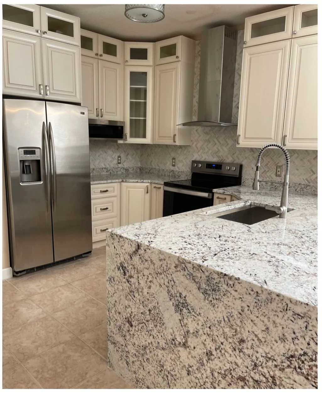 After: Kitchen after the remodel: cherry cabinets replaced with cream cabinets and a white granite waterfall island
