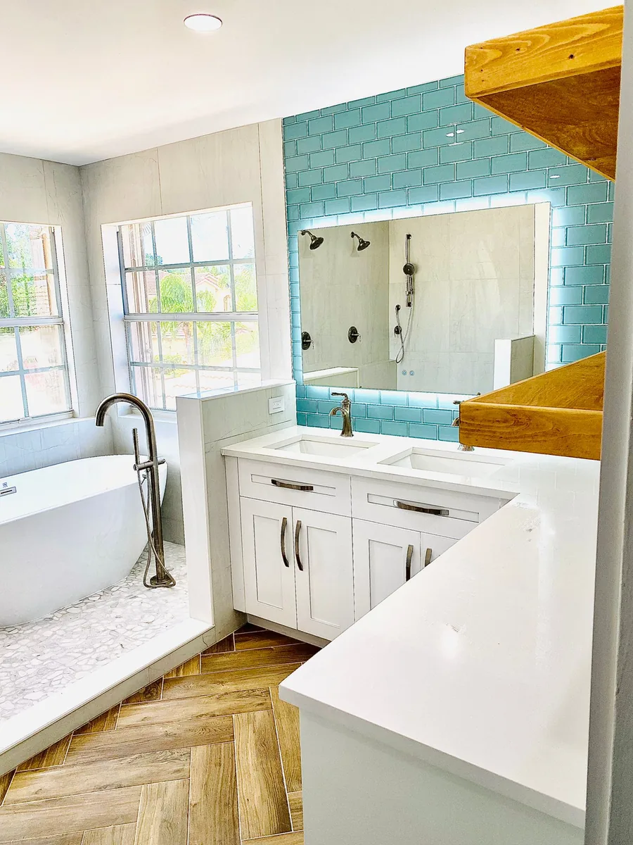 Bathroom with teal subway tile, LED mirror and herringbone wood look floor