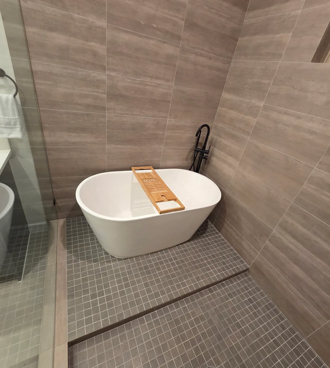 Freestanding soaking tub with a floor mounted filler on mosaic tile