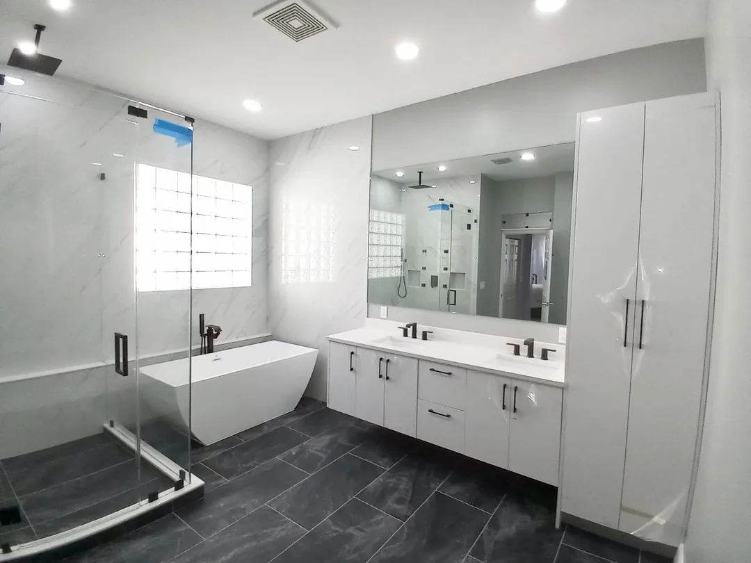 Bathroom with a glass enclosed shower and tub, floating white vanity and dark floor