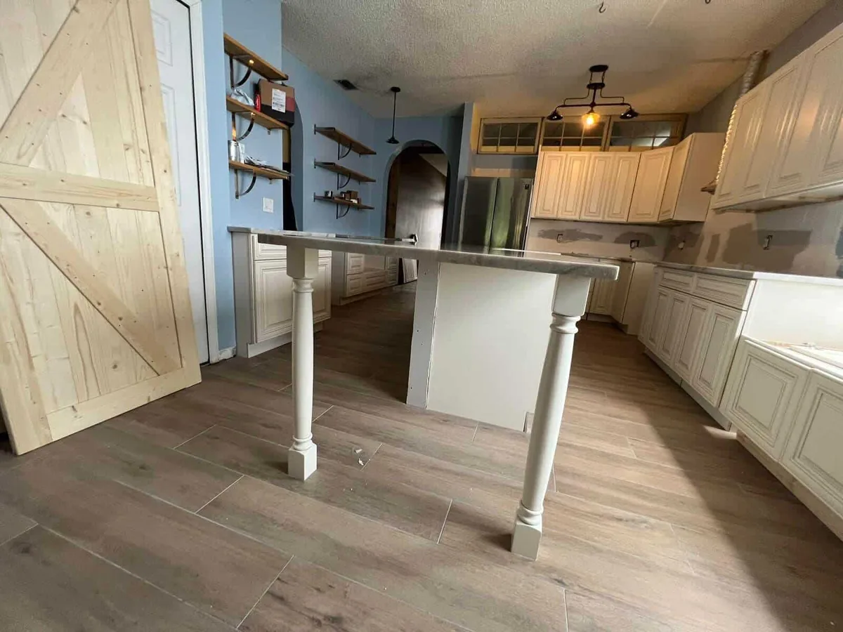 Kitchen island with turned legs and a barn door during installation