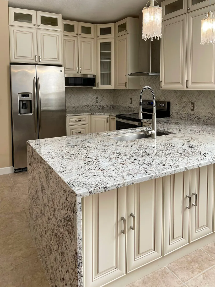 Cream raised panel kitchen with a white granite island