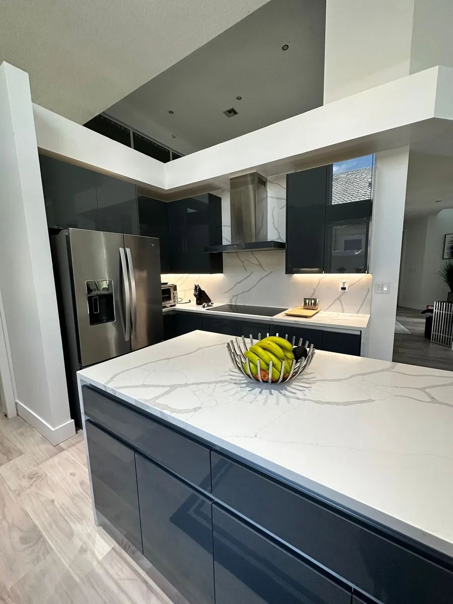 Close view of a white veined quartz island with dark gloss drawer fronts