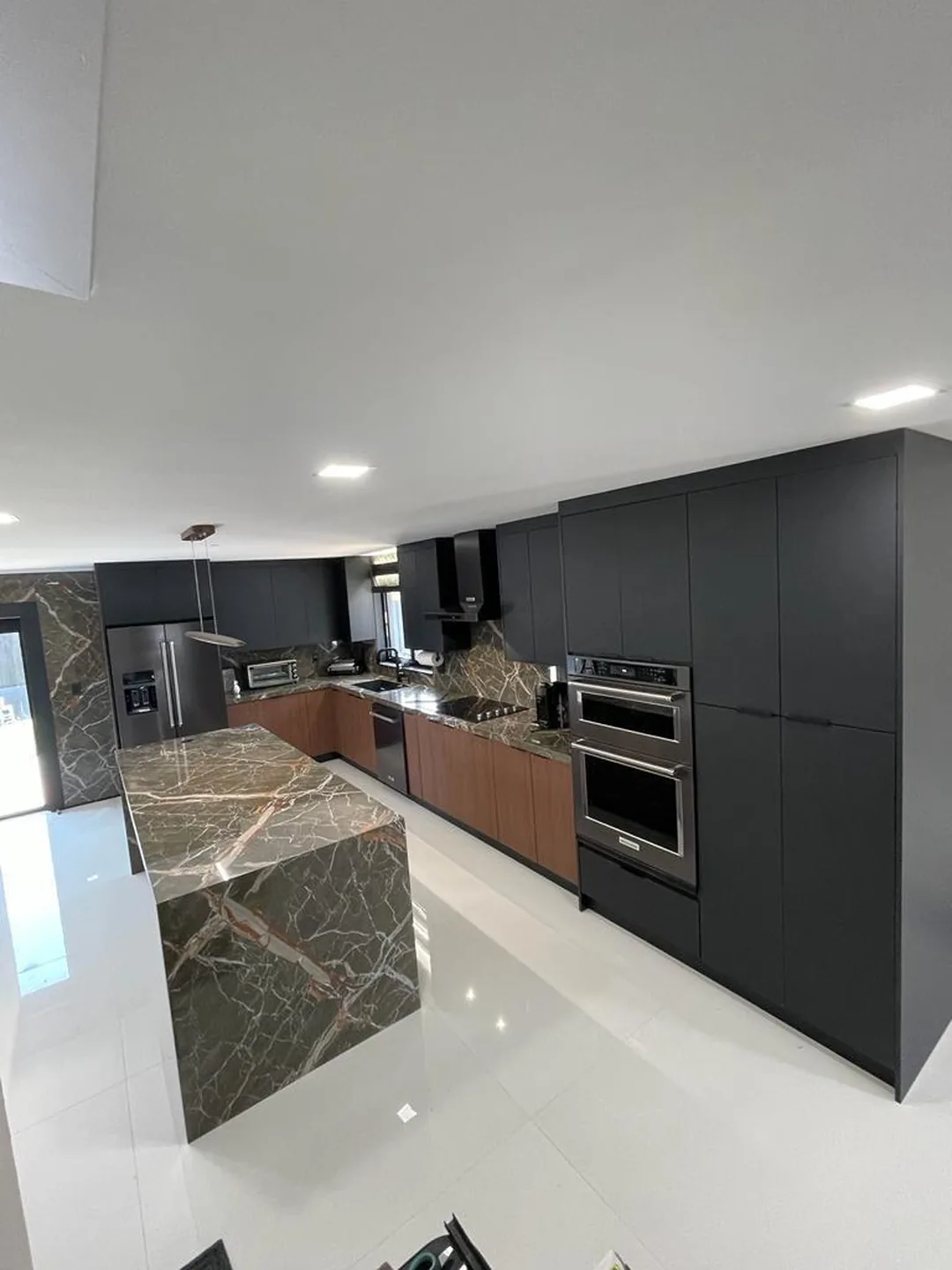Charcoal kitchen with a green and brown marble waterfall island