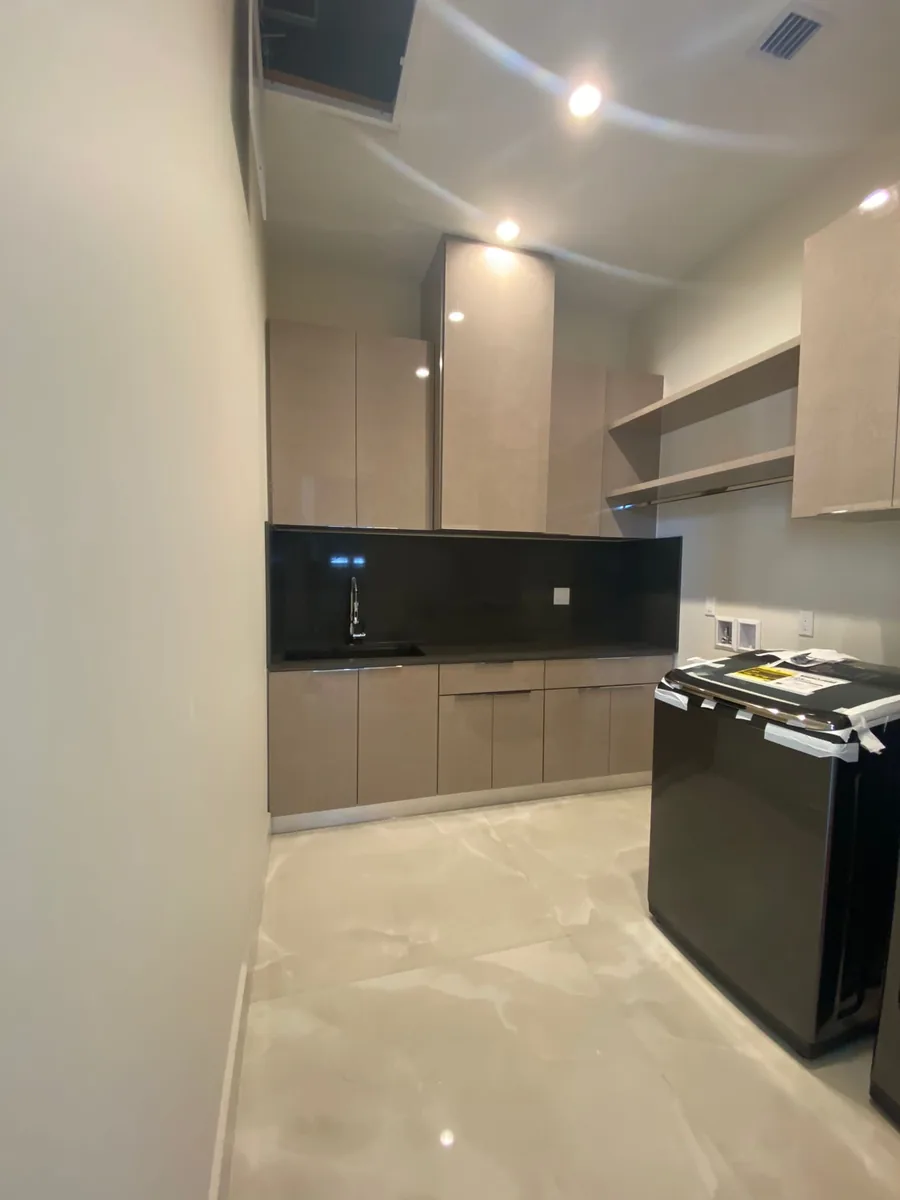 Galley kitchen with taupe flat panel cabinets and a black backsplash