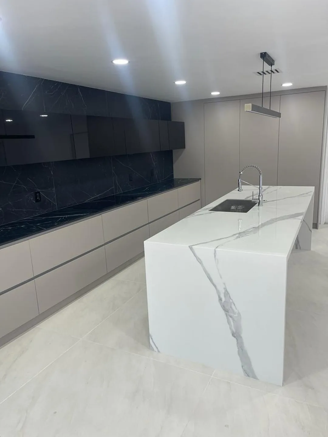 White waterfall island in front of a navy gloss cabinet wall