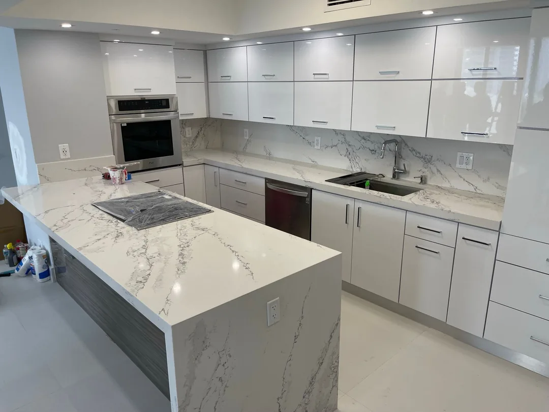 White gloss kitchen with a calacatta quartz waterfall island and cooktop
