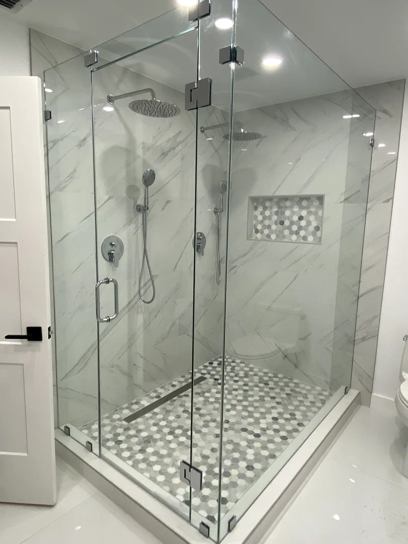 Frameless glass shower with marble look walls, rain head and mosaic floor