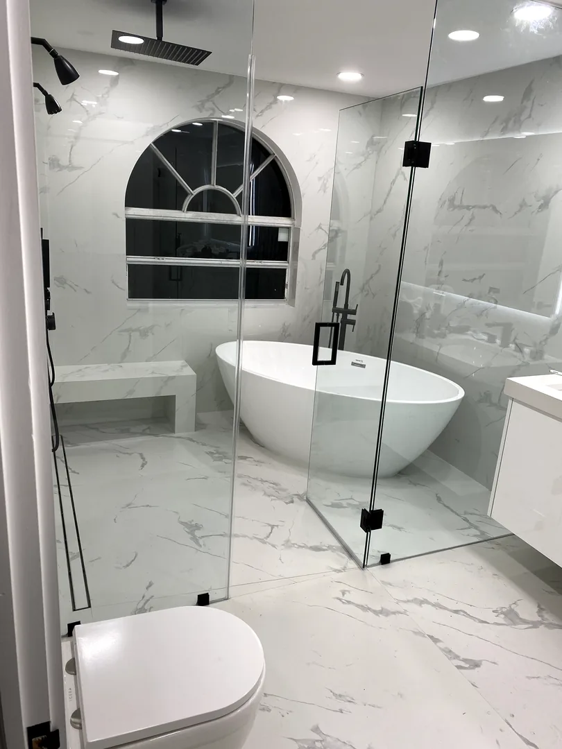 Glass enclosed wet room with a freestanding tub and arched window
