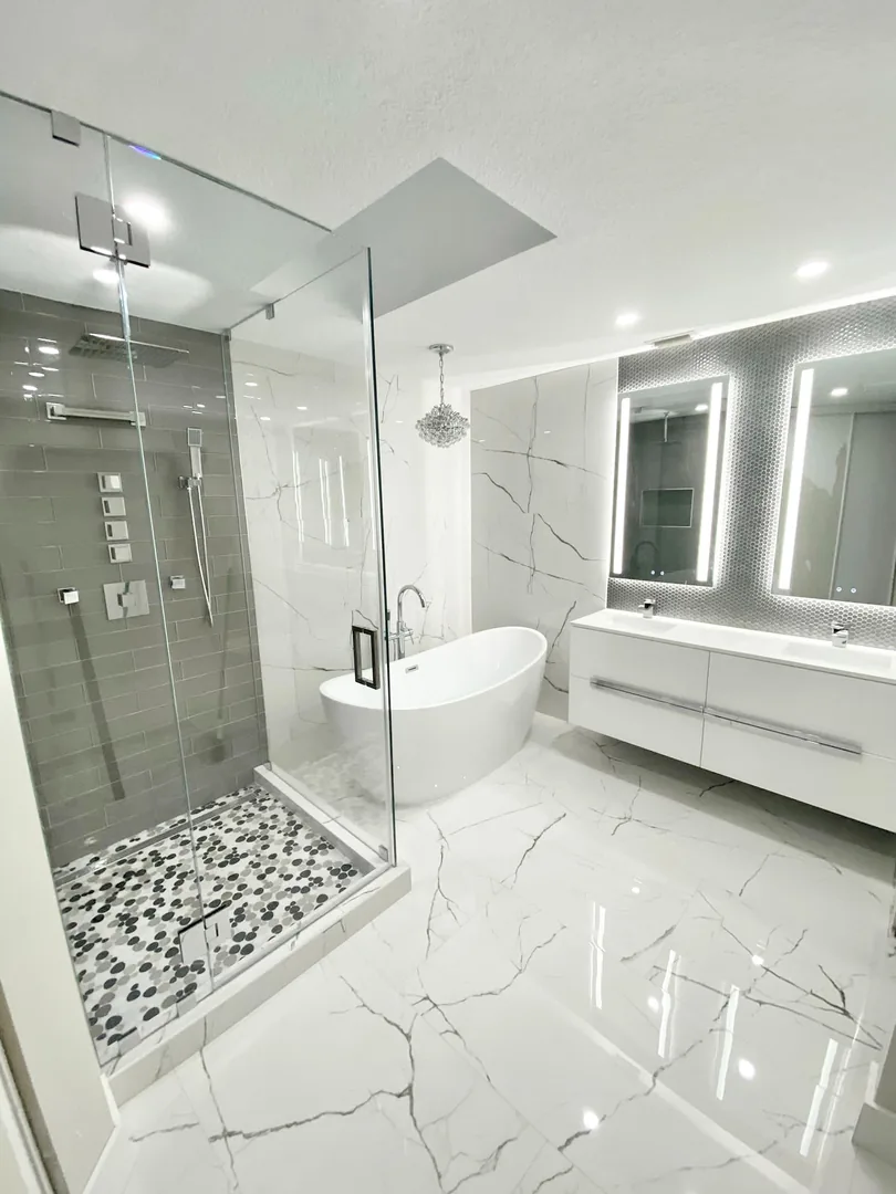 Frameless glass shower beside a freestanding tub and floating vanity